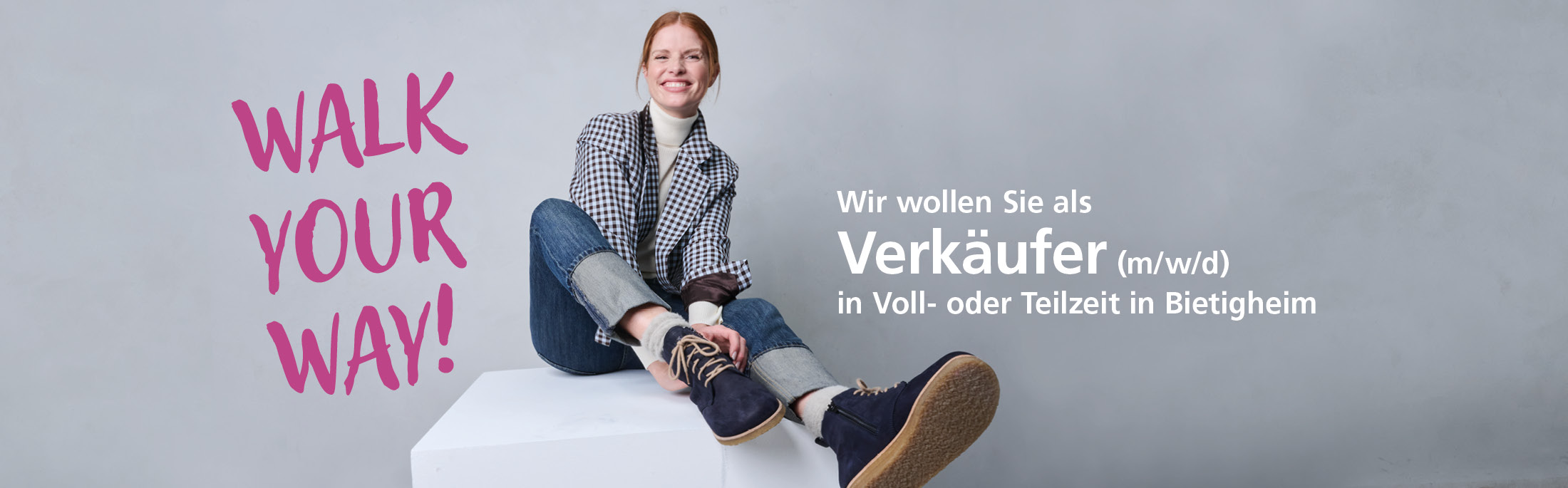 Junge Frau sitzt lächelnd auf einem Podest. Text auf dem Bild: "Walk your way! Wir wollen Sie als Verkäufer (m/w/d) in Voll- oder Teilzeit in Bietigheim."