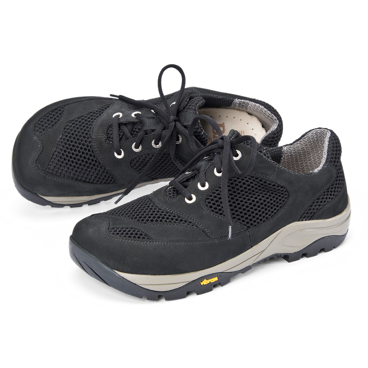 Bequeme schwarze Wanderschuhe mit Mesh-Einsätzen und Vibram-Sohle Ein Paar schwarze Wanderschuhe mit Schnürsenkeln, Mesh-Einsätzen und robuster Vibram-Sohle auf weißem Hintergrund