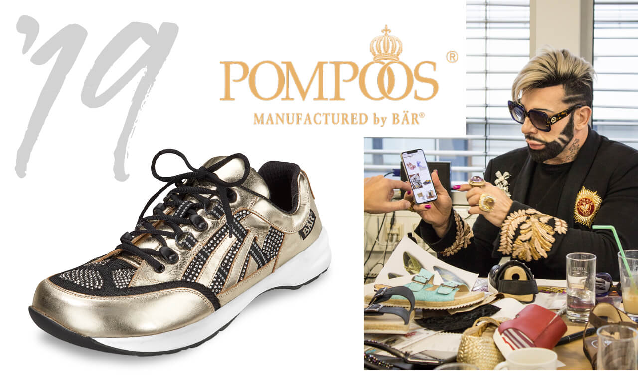 Goldener Sneaker mit edlen Verzierungen von Pompoos by Bär Goldener Sneaker von Pompoos by Bär, daneben eine Person mit Smartphone und luxuriösem Outfit