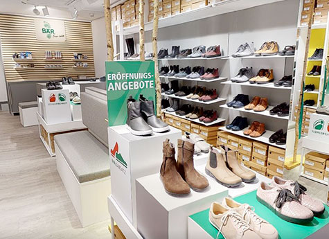 Schuhauswahl im neuen Laden zur Eröffnung Innenansicht eines Schuhgeschäfts mit Eröffnungsangeboten, verschiedenen Stilen und Farben auf Regalen ausgestellt.